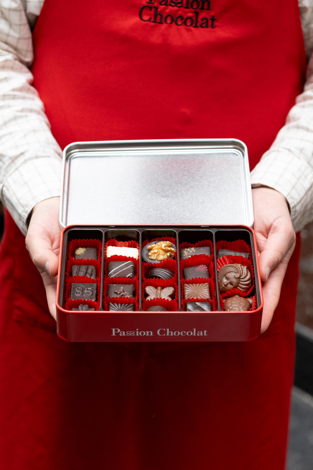 Coffret de pralines Passion Chocolat tenu dans un tablier rouge