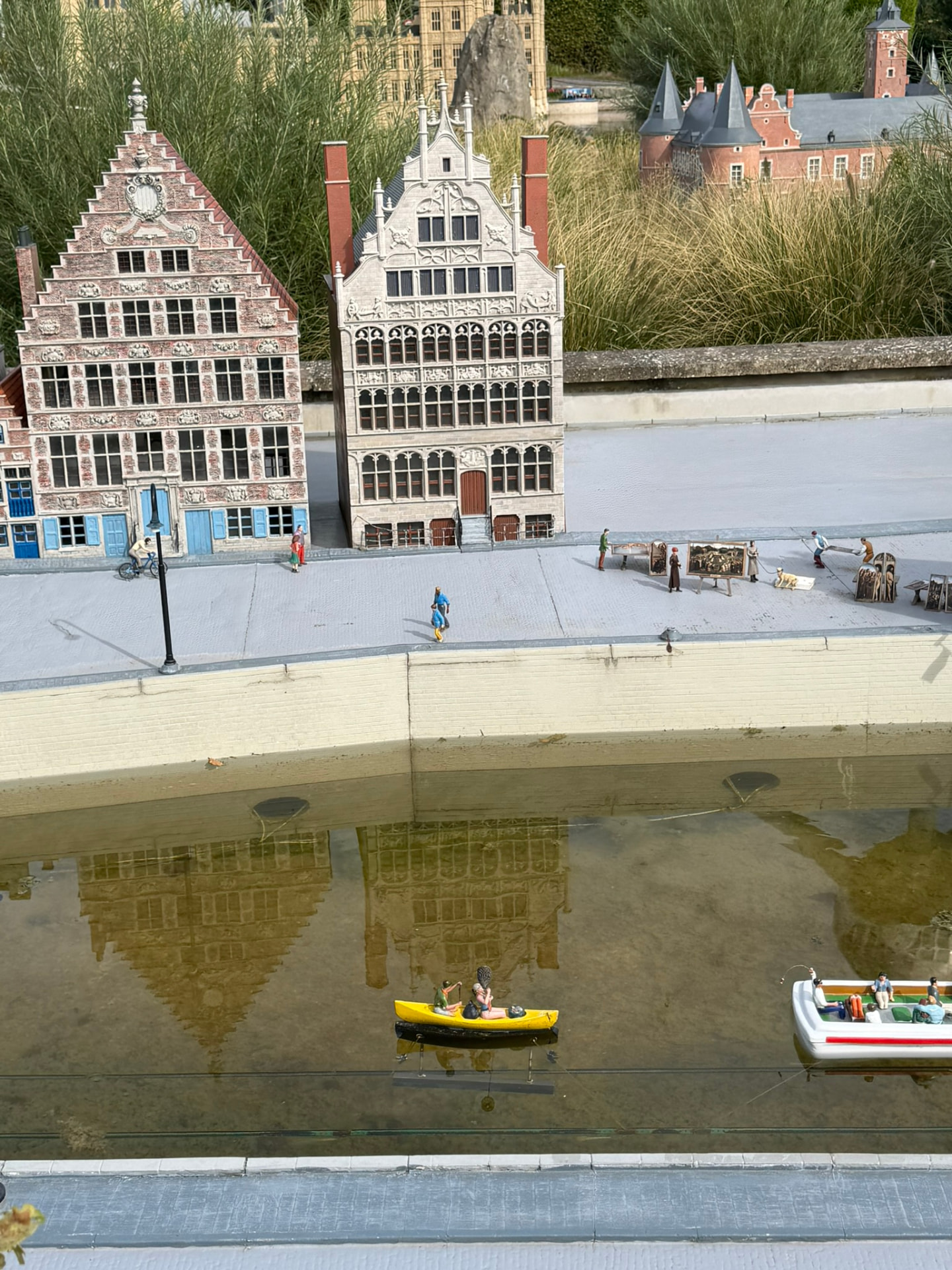 Des maisons à pignons miniatures au bord d’un canal, avec un kayak jaune