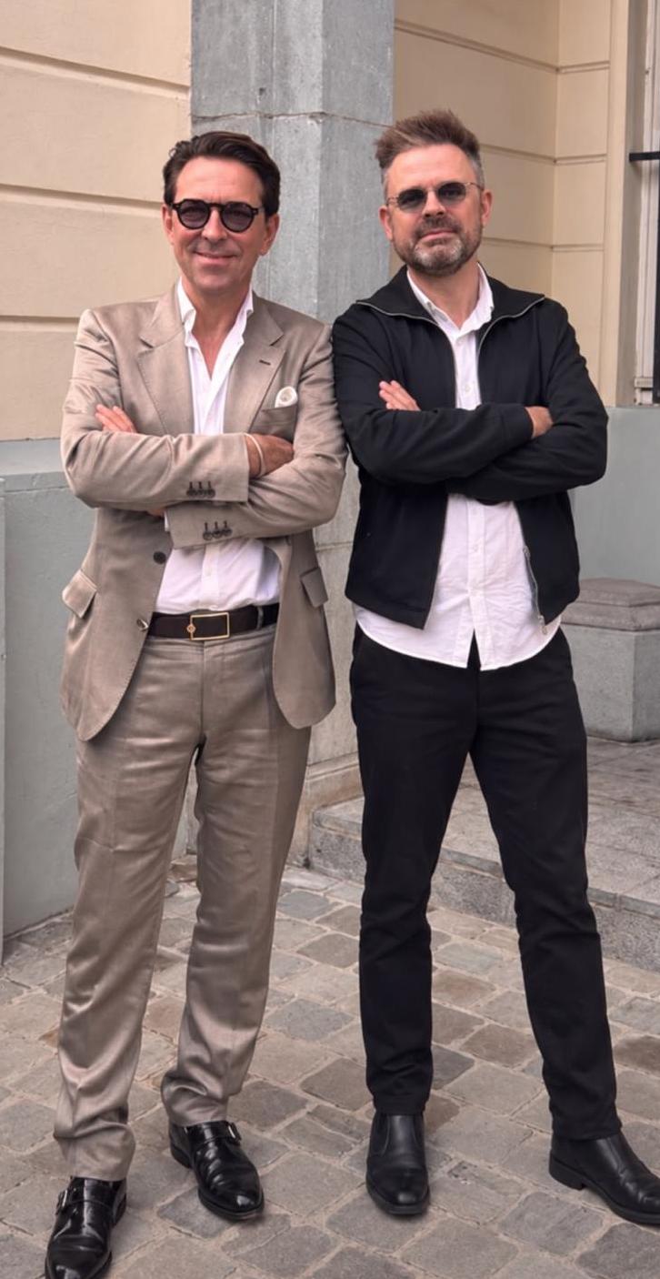 Foto ten voeten uit: Carl De Moncharline en Sébastien Boussois voor een lichte gevel, armen gekruist