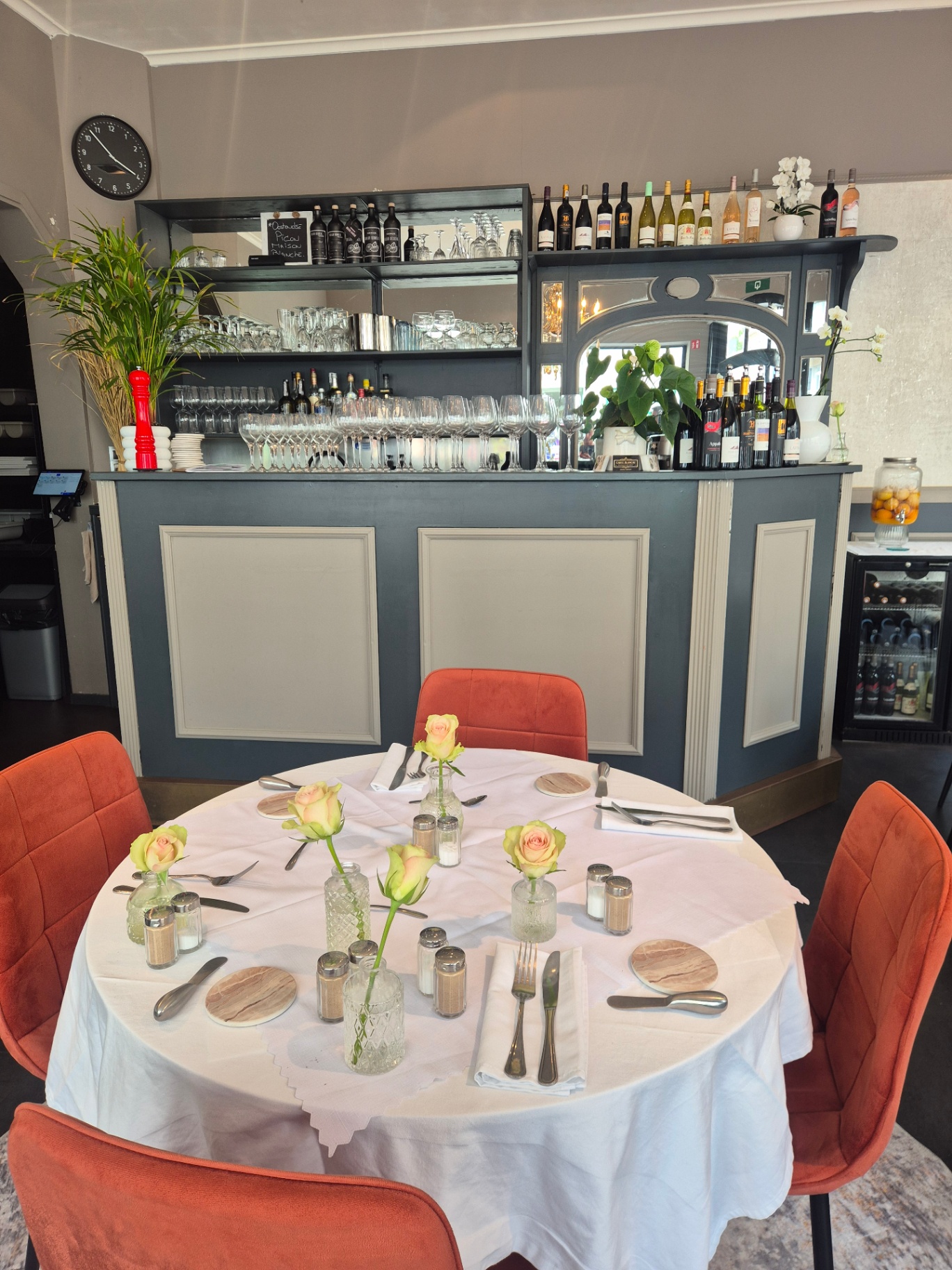 Salle intérieure de Carte Blanche : bar bleu nuit, verres alignés, chaises orange Salle intérieure de Carte Blanche : bar bleu nuit, verres alignés, chaises orange