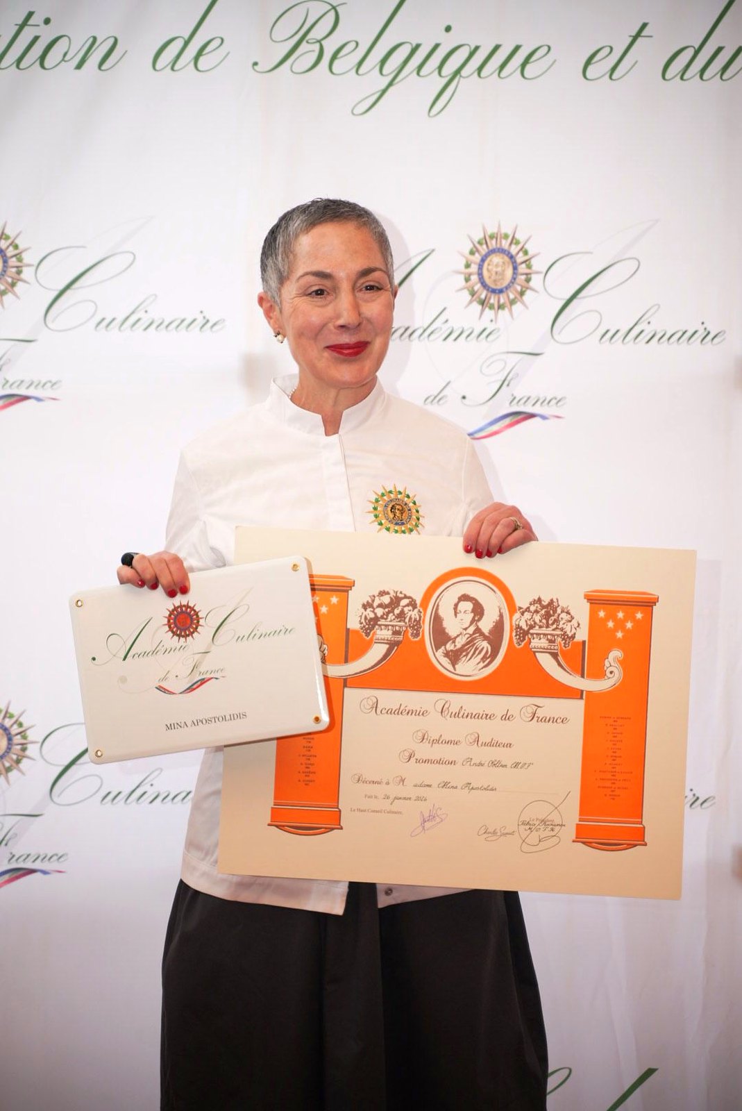 Chef Mina Apostolidis holding her Académie Culinaire de France diploma and plaque