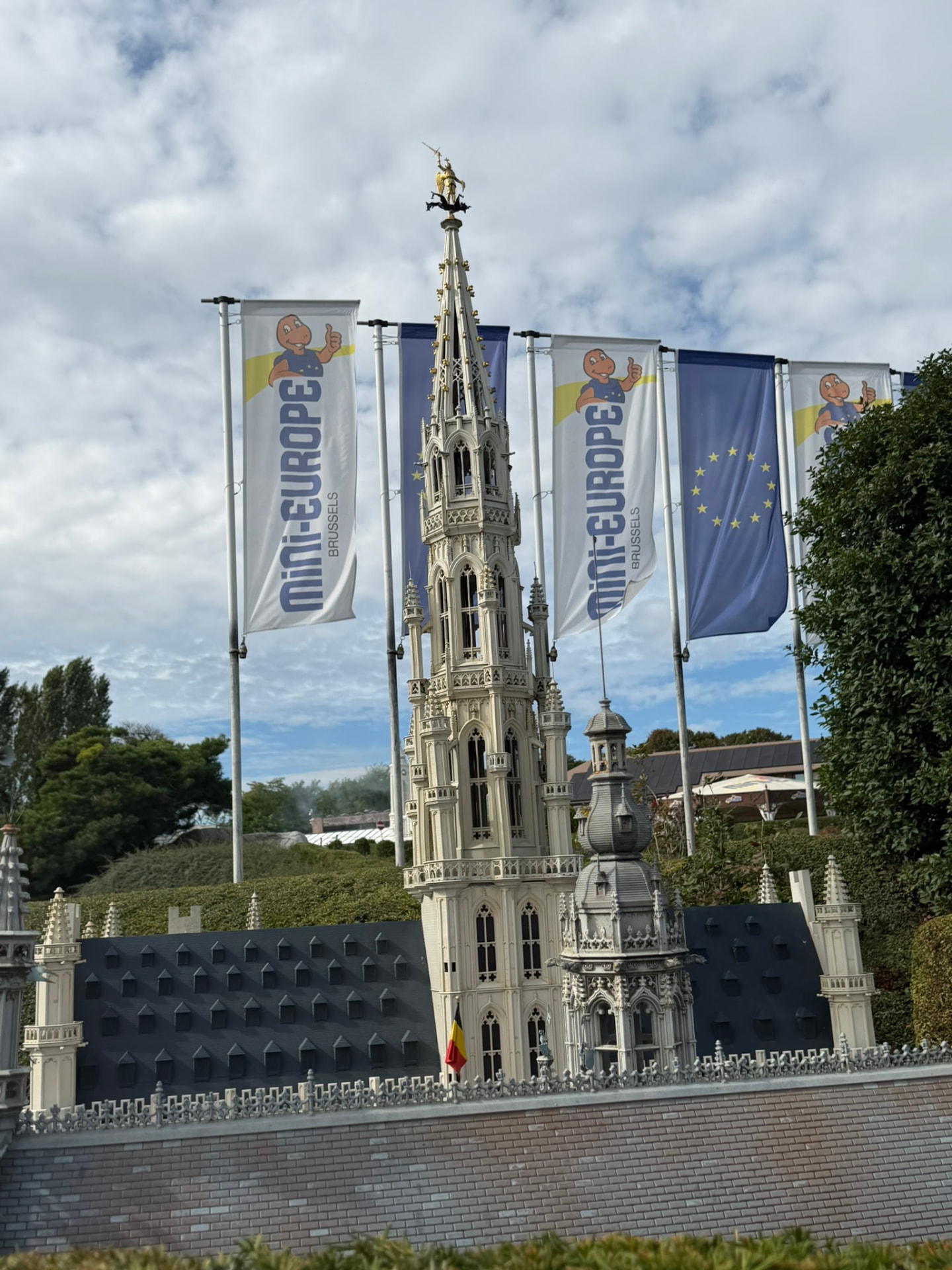La tour de l’hôtel de ville de Bruxelles miniature entre les drapeaux de Mini-Europe et de l’Union européenne