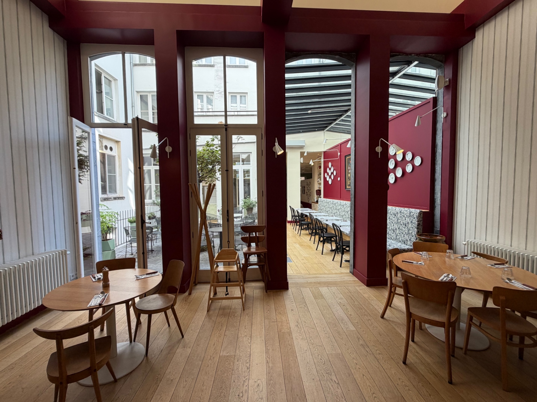 Salle de Sina Pasta aux boiseries bordeaux ouverte sur la verrière