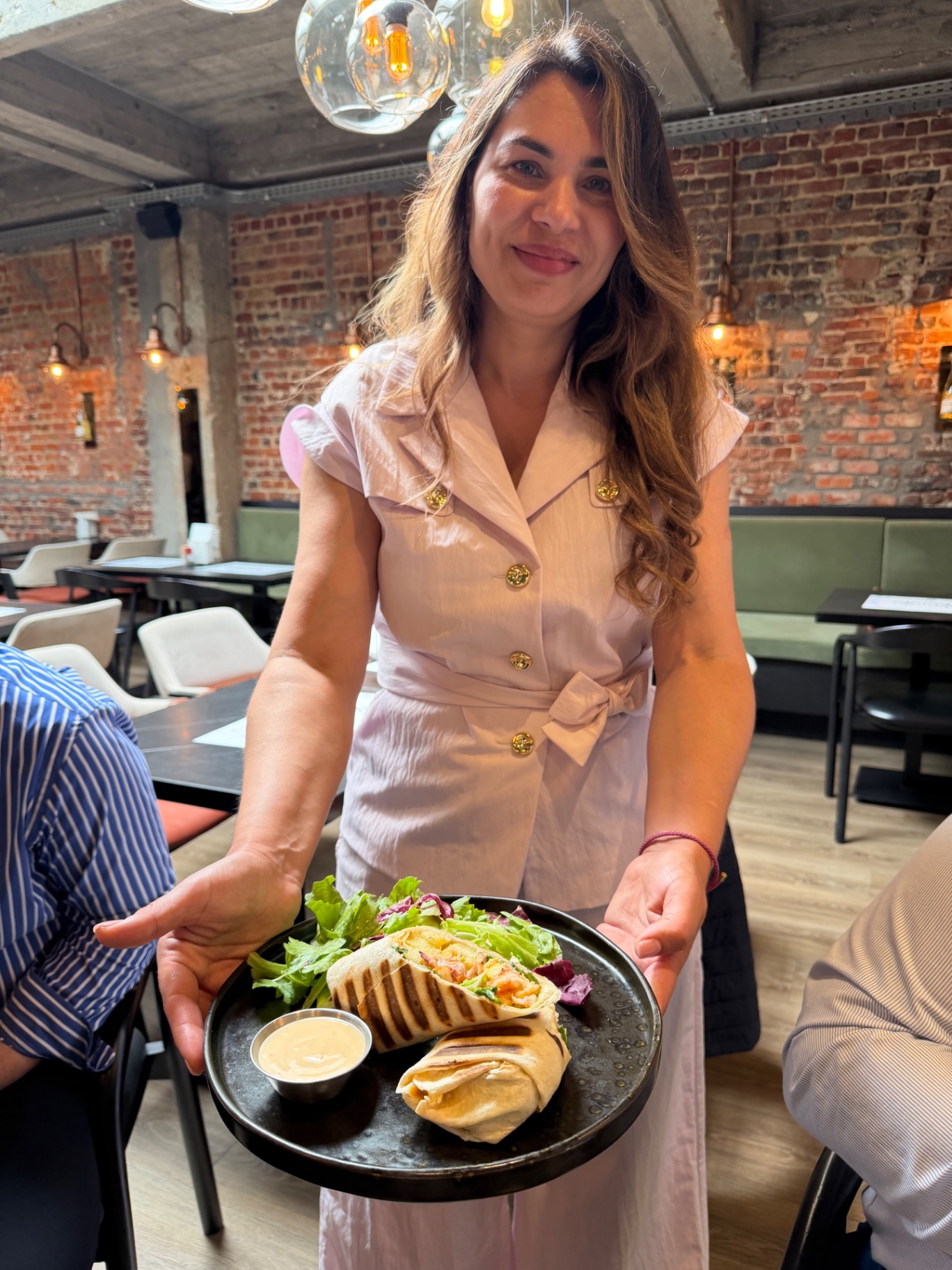 Membre de l’équipe Pescobar présentant un wrap aux crevettes pané et grillé avec salade et sauce dippy