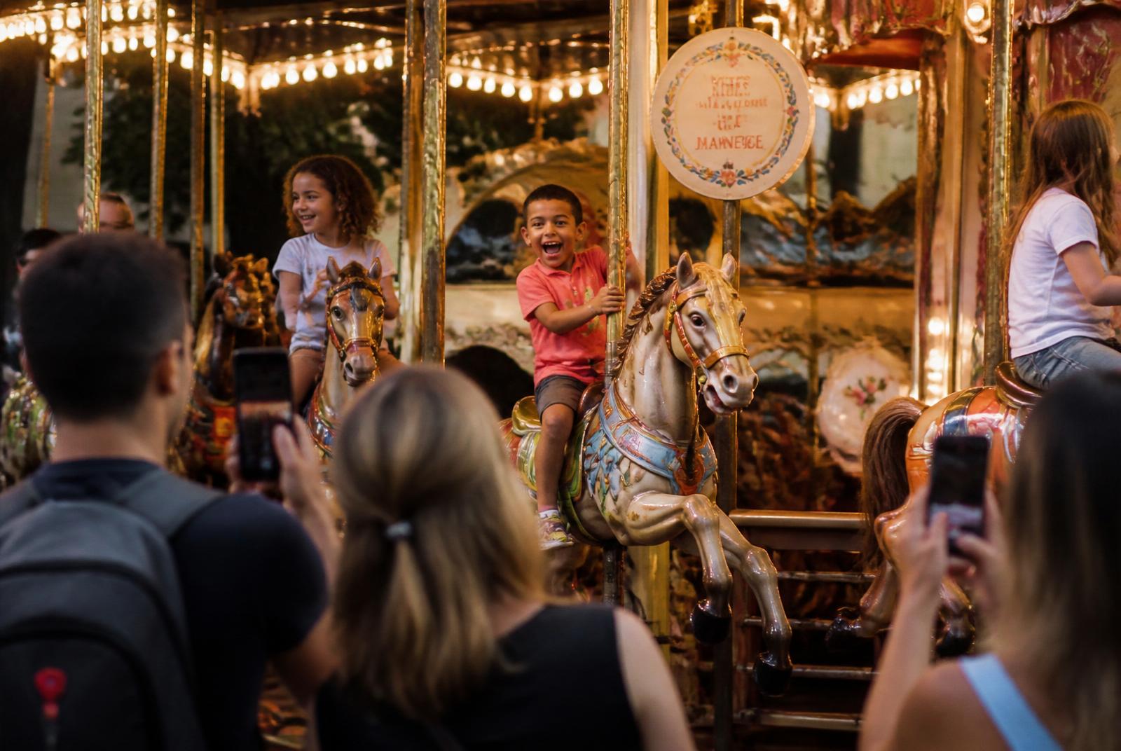 Enfants riant sur un manège de chevaux de bois à la Foire du Midi