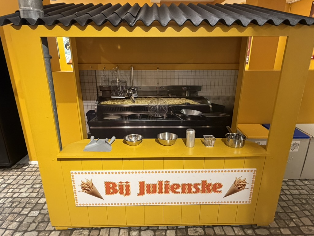 Bright yellow Bij Julienske fry stall inside the Friet Museum Brussels