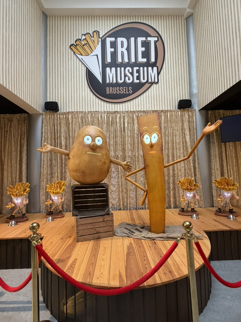 Potato and fry mascots on the welcome stage under the Friet Museum Brussels logo