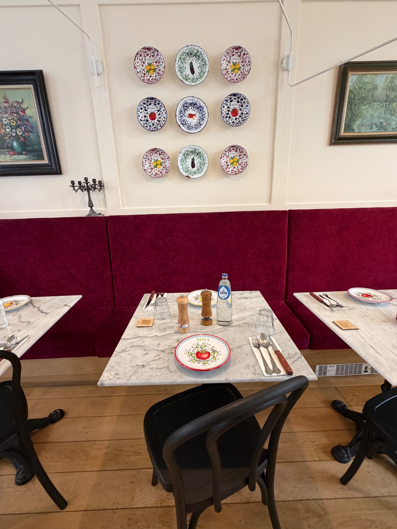 Salle Sina Pasta avec banquette velours framboise et assiettes siciliennes au mur