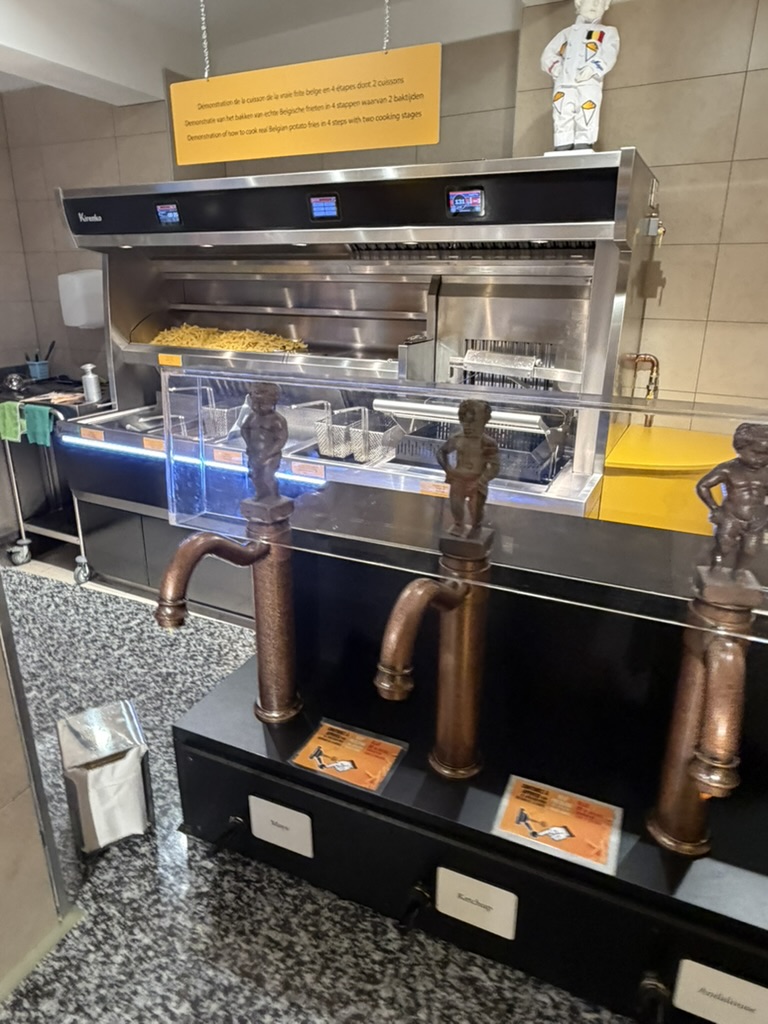 Copper sauce taps topped with Manneken Pis figures at the Friet Museum